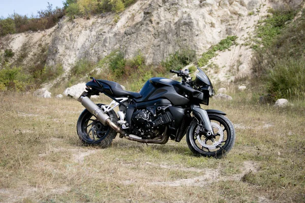 A motocicleta preta fica no fundo de uma carreira no verão — Fotografia de Stock