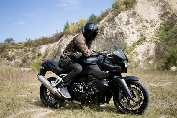 Voyage à moto à travers une carrière. Le motocycliste portant un casque sur une moto — Photo