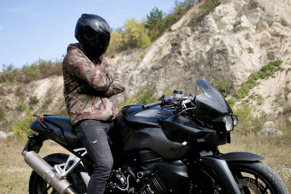 Viagem a uma motocicleta através de uma carreira. O motociclista usando um capacete em uma motocicleta — Fotografia de Stock
