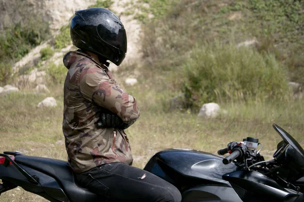 Viagem a uma motocicleta através de uma carreira. O motociclista usando um capacete em uma motocicleta — Fotografia de Stock