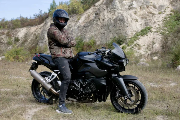 Viagem a uma motocicleta através de uma carreira. O motociclista usando um capacete em uma motocicleta — Fotografia de Stock