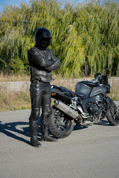 Bir motosiklet kask giymiş siyah motosikletçi görünüyor