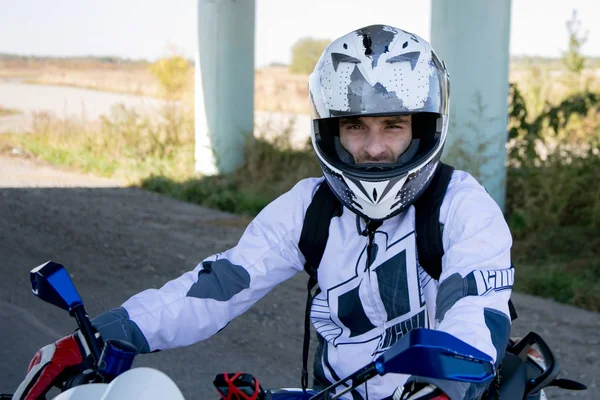 O motociclista de capacete numa mota. Viagem a uma motocicleta. Motociclista fica na estrada — Fotografia de Stock