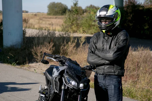 O motociclista de capacete numa mota. Motociclista fica na estrada — Fotografia de Stock