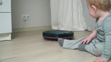 Ahşap zemin üzerinde erkek bebek ile katta robot elektrik süpürgesi