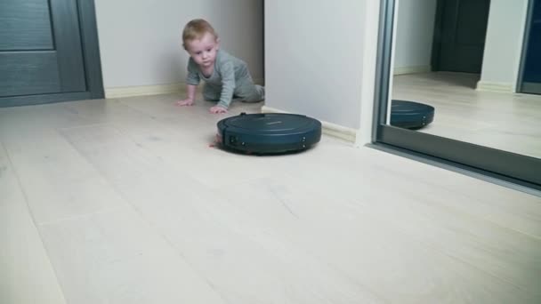 Robot stofzuiger op vloer met babyjongen op de houten vloer — Stockvideo