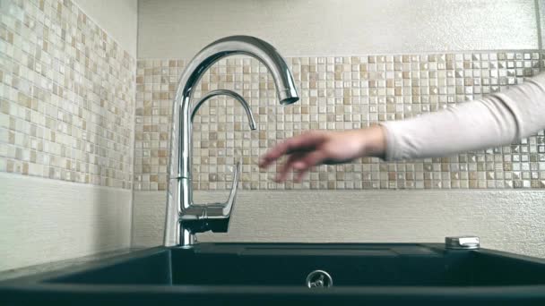 Chiudi le mani femminili aprendo il rubinetto dell'acqua in cucina. Acqua di rubinetto da un lavandino in una cucina — Video Stock