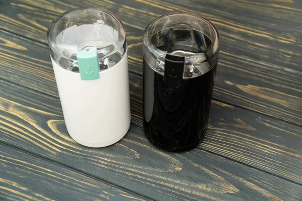 İki kahve değirmenleri fasulye izole ahşap masalarında