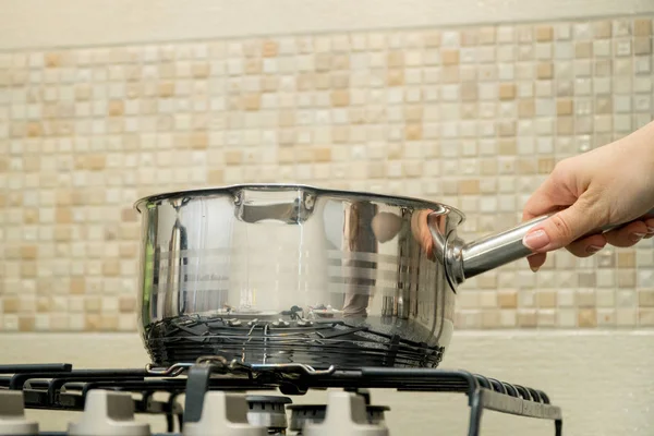 Kadının el büyük pot modern mutfakta tutar.