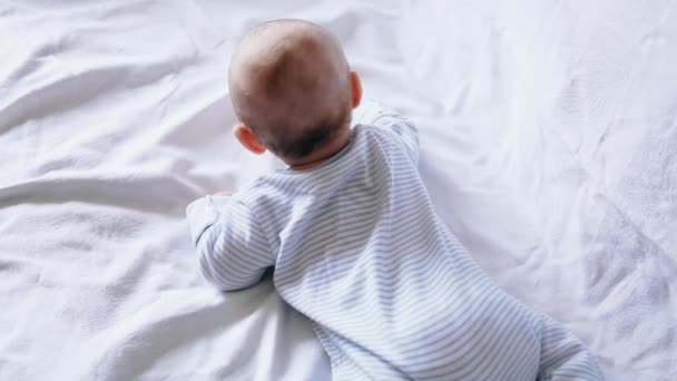 Lindo niño feliz de 4 meses de edad mintiendo y jugando en una cama blanca — Vídeos de Stock