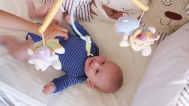 Lindo niño feliz de 6 meses mintiendo y jugando. Pequeño niño mirando sus juguetes — Vídeo de stock