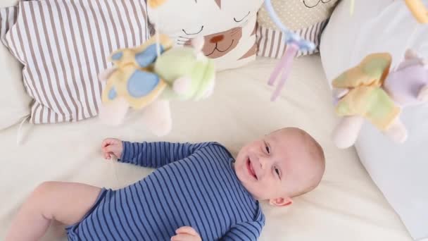 Lindo niño feliz de 6 meses mintiendo y jugando. Pequeño niño mirando sus juguetes — Vídeos de Stock