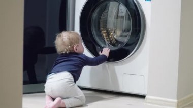 Bebek çocuk bir yaşındaki çocuk çamaşır makinesi ev arıyorum. Ev aletleri sorunları. Erkek bebek çamaşır makinesi açar