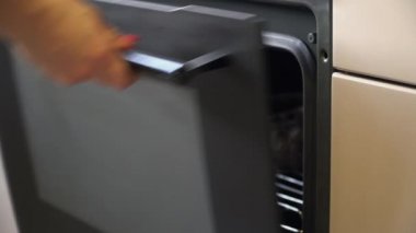 Pişmiş et sıcak fırın dışında bir kadın. Yiyecek hazırlama elektrik konveksiyon fırın ile. Yan görünüm