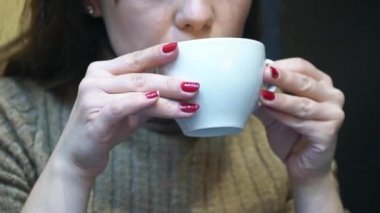 Restoranda sıcak kahve içen genç bir kadın.