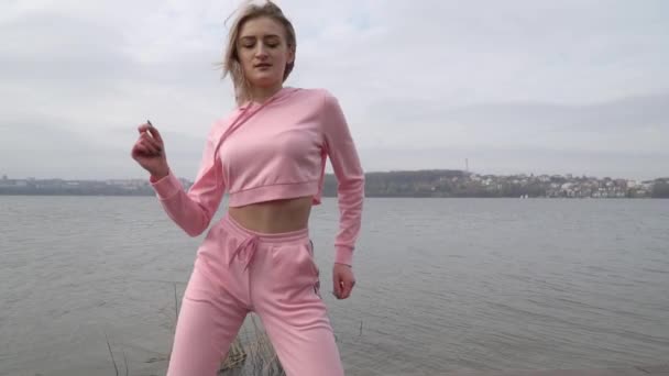 Счастливая молодая танцовщица кавказская девушка на розовой городской улице танцует фристайл в городе у озера — стоковое видео