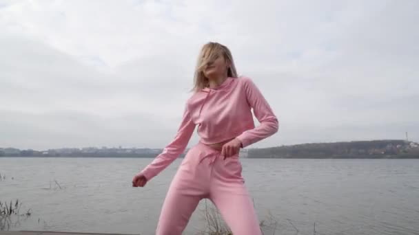 Heureuse jeune danseuse caucasienne fille en rose urbaine danse de rue freestyle dans la ville au bord du lac — Video