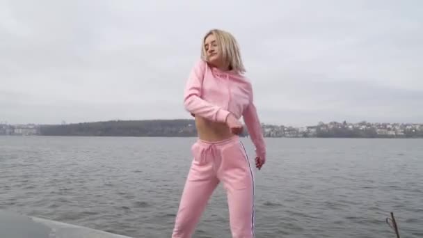 Šťastná mladá dívka v městské ulici tančí volný styl do ve městě u jezera — Stock video