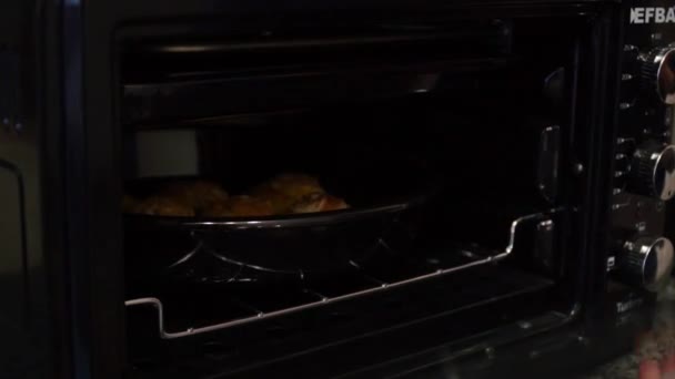 Woman taking baking tray with cupcakes from oven — Stock Video