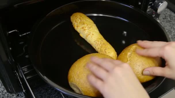 Женщина берет из духовки пекарню в форме пениса на подносе для выпечки — стоковое видео