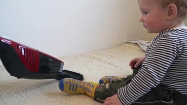 男の子は、母親が掃除機を掃除するまで掃除機で遊んでいます — ストック動画