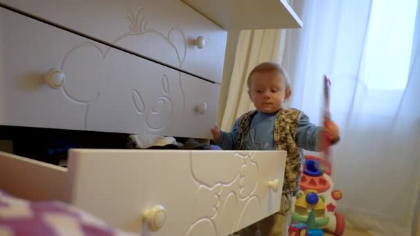 Забавный маленький мальчик получает чистые вещи из шкафа — стоковое видео