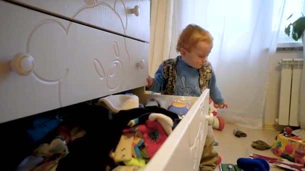 Lustige niedliche kleine Junge bekommt saubere Dinge aus dem Kleiderschrank — Stockvideo