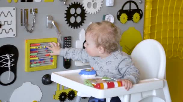 Bébé garçon mignon jouant avec la carte occupée sur le mur. Plateau de jeu en bois — Video