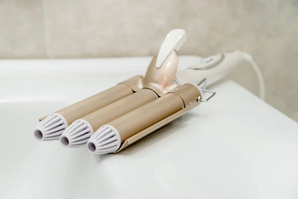 Brown hair straightener in a bathroom. Hair care — Stock Photo, Image