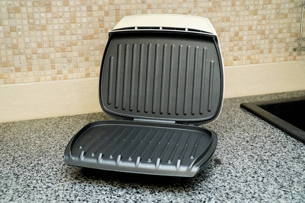 Gri mutfak masasında beyaz elektrikli ızgara.