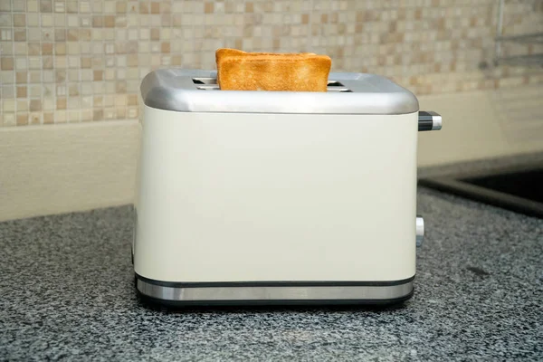 Toaster with toasted bread for breakfast inside. Gray table