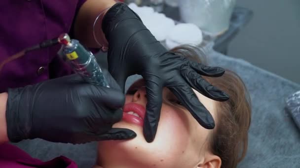 Ung kvinna med permanent makeup på läpparna. Kosmetolog tillämpa permanent makeup på läpparna — Stockvideo