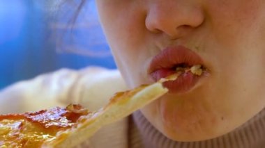 Genç bir kadın bir parça pizzayı ısırır ve çiğner. Yavaş çekim