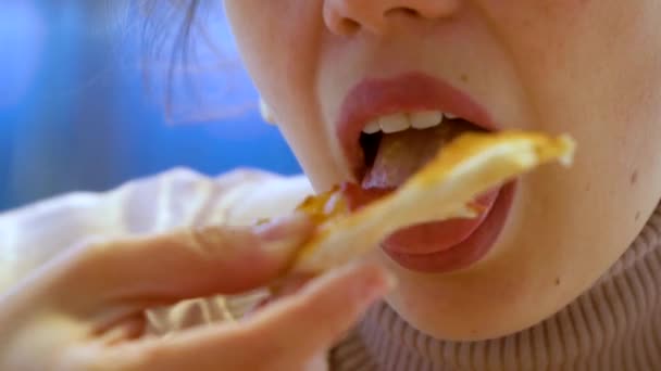 A young caucasian woman bites a piece of pizza and chews it. Slow motion — Stock Video