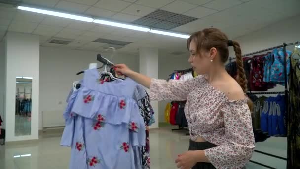 Hermosa mujer eligió un vestido en la tienda. Chica de compras — Vídeos de Stock