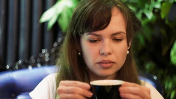 Jonge vrouw die warme thee drinkt in restaurant — Stockvideo