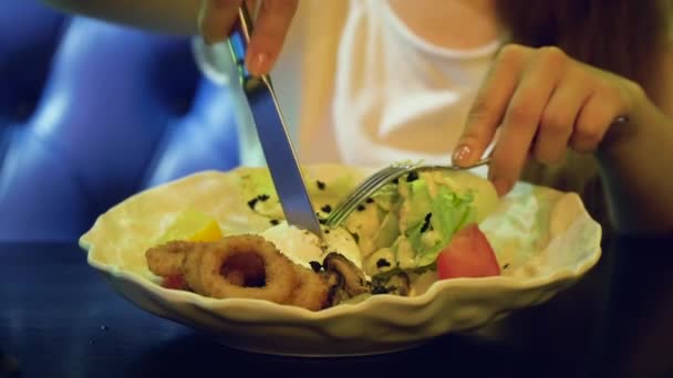 Mujer joven comiendo ensalada fresca en un restaurante de lujo. Niña cortando huevo con cuchillo y tenedor — Vídeos de Stock