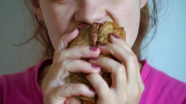 Mujer joven comiendo sándwich de comida rápida con placer en la cafetería — Vídeos de Stock