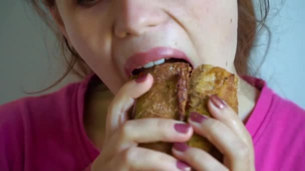 Mujer joven comiendo sándwich de comida rápida con placer en la cafetería. Movimiento lento — Vídeos de Stock