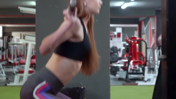 Chica culturista bombea el cuerpo con una barra. Hermosa chica en el club deportivo hace diferentes tipos de ejercicios en los simuladores. Chica deportiva haciendo ejercicio en cuclillas en el gimnasio — Vídeo de stock