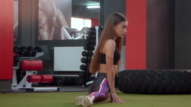 Chica atlética sentada sobre cuerda en el gimnasio. Ejercicios estáticos de estiramiento para deportistas — Vídeos de Stock