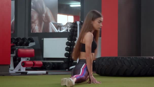 Statische Dehnübungen für Sportler. athletisches Mädchen sitzt auf Bindfäden in Turnhalle — Stockvideo