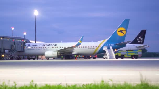 LVIV, UKRAINE - 26 MAI 2019 : Avion passant par un autre avion stationné à la porte de l'aéroport international de Lviv. Deux voitures de sécurité à l'avant — Video