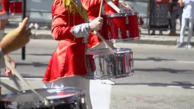 Şehir caddesinde kırmızı kostümlü davulcu kızların şenlikli yürüyüşünde sokak performansı