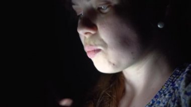 Mutlu kız gülümsüyor ve karanlıkta telefon öper. Kız iyi haber öğrendim