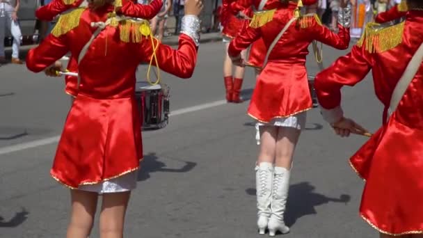 若いドラマーが並んでメロディーを叩く。街路で赤い衣装を着たドラマーの女の子のお祝いの行進のストリートパフォーマンス。バックビュー — ストック動画