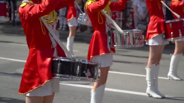 Chicas jóvenes baterista en rojo en el desfile. Primer plano de las manos femeninas bateristas están golpeando en el tambor de sus palos — Vídeo de stock