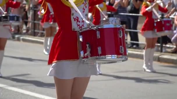 街路で赤い衣装を着たドラマーの女の子のお祝いの行進のストリートパフォーマンス。女性の手のドラマーのクローズアップは、彼らの棒のドラムでノックしています。スローモーション — ストック動画