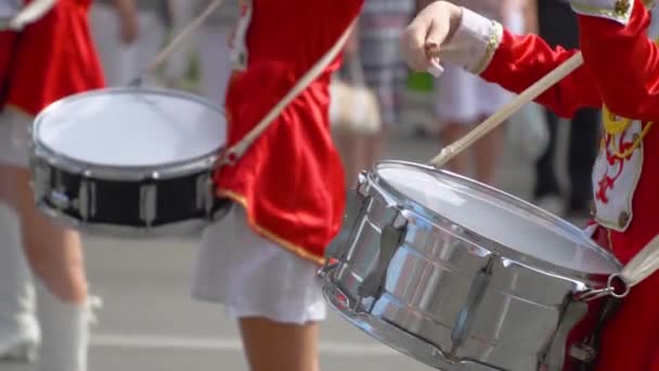 Närbild av kvinnliga händer trummisar knackar i trumman av sina pinnar. Street Performance av festliga marsch av trummisar flickor i röda kostymer på City Street. Slow motion — Stockvideo