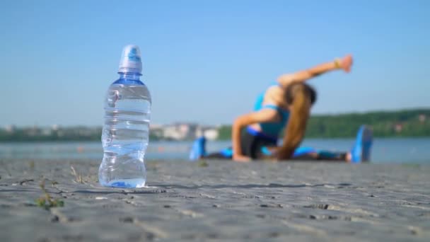 Das Mädchen sitzt auf einem Bindfaden am See. Wasser im Vordergrund — Stockvideo
